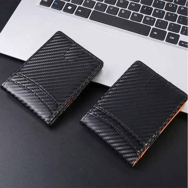 Black textured credit card holder wallet placed on a dark surface next to a laptop keyboard
