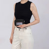 A woman wearing a black tank top and white pants holds an Iris Checkered Wallet with ID window.
