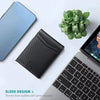 A black slim wallet is shown next to a silver smartphone and a potted green plant on a white surface.
