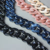 A close-up of multiple acrylic resin detachable bag chain straps in shades of black, dark blue, pink, and cream.
