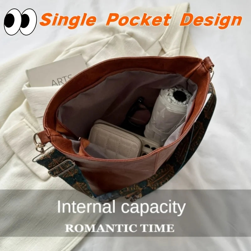 A brown leather single pocket design crossbody bag with a patterned strap shown open to reveal internal capacity.