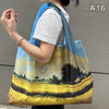 A woman holds a large yellow and blue fabric shopping tote bag against a gray wall.