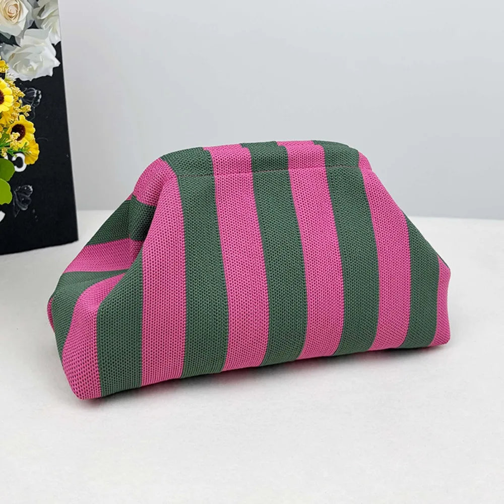 A pink and green striped knit cloud makeup bag lying on a white surface.