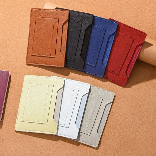 A set of five slim travel wallets in various shades of brown, black, blue, and red are displayed on a tan surface.