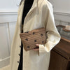 A beige trench coat is shown wearing a brown embroidered makeup pouch.