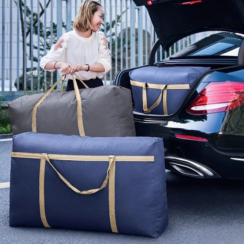 Two navy blue storage bags are placed on the ground next to a black car, with a woman in a white top standing nearby.