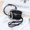 Black leather coin purse with silver chain and lanyard resting on a map and books.