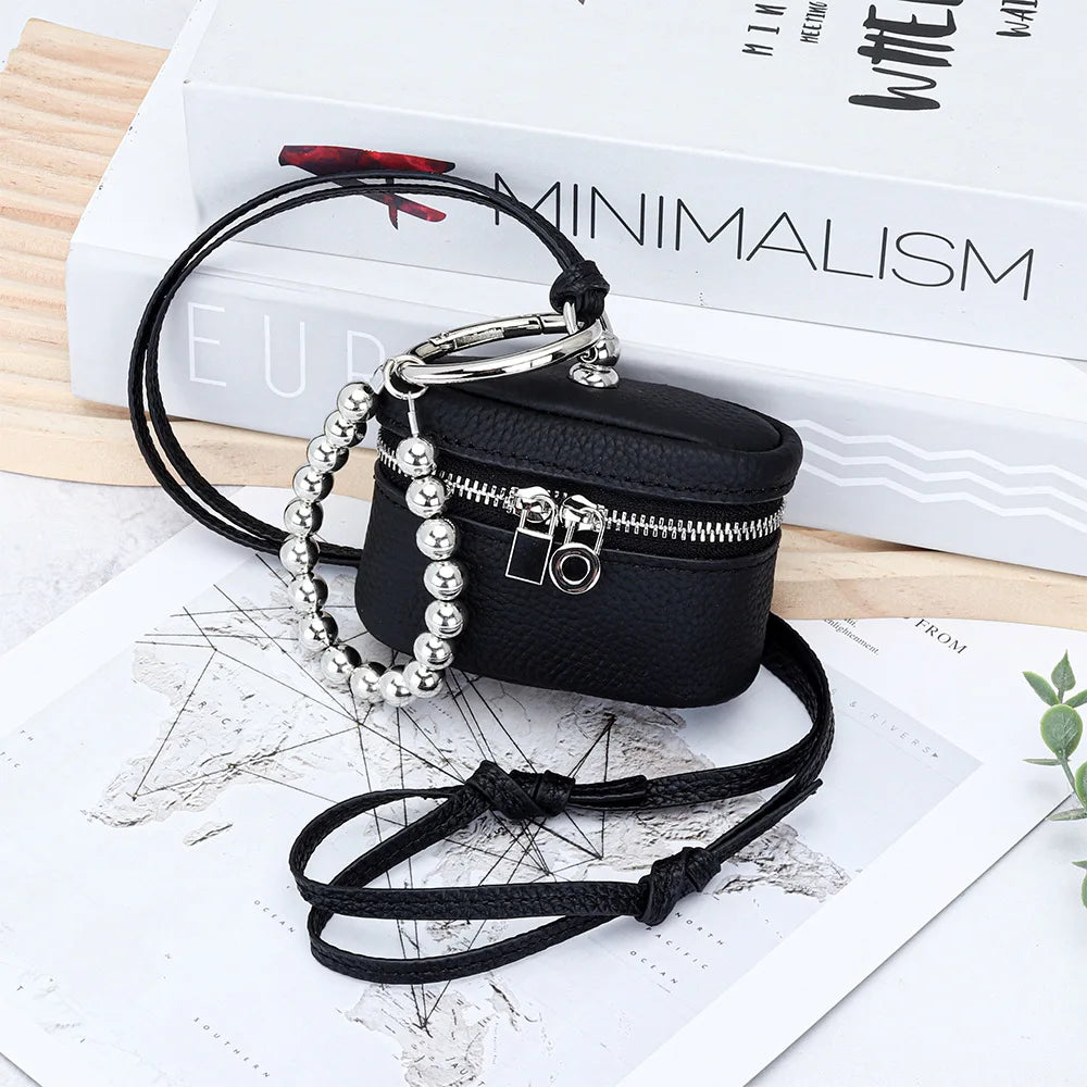 Black leather coin purse with silver chain and lanyard resting on a map and books.