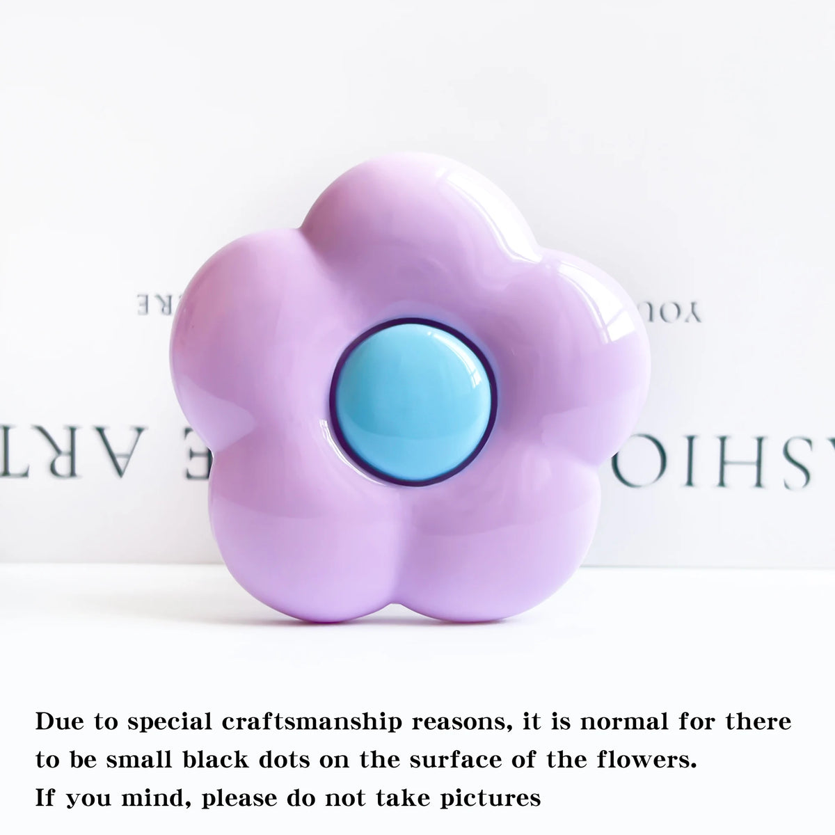 A soft purple flower shaped phone grip ring stand with small black dots on the surface.