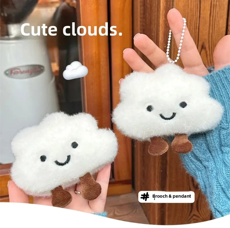 A hand holds a white cloud-shaped plush keychain with brown feet against a wooden background.
