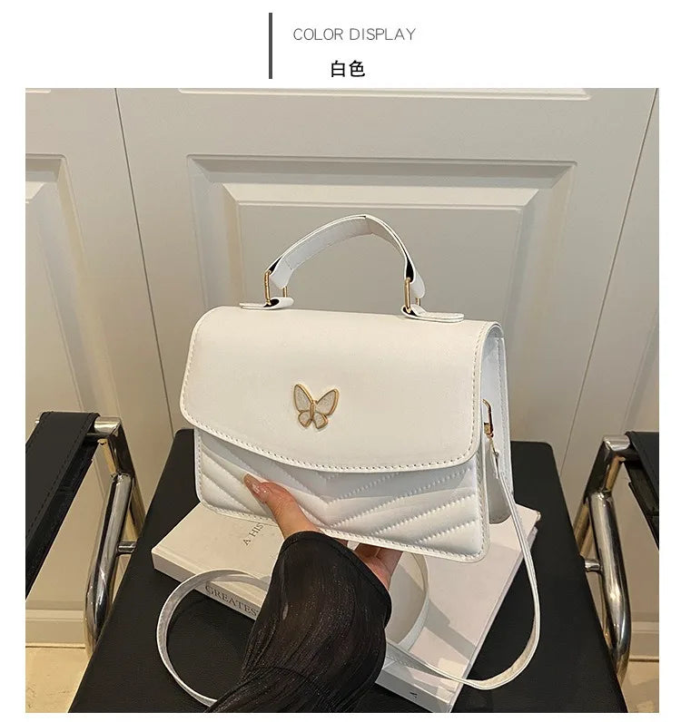 A white women's solid texture shoulder messenger bag is displayed against a light background.