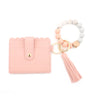 A pink silicone bead bracelet is shown next to a leather card holder with a tassel.