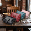 A collection of leather mini wallets in various colors and shades with gold clover charms resting on a wooden table.
