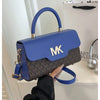A woman holds a blue Michael Kors letter square crossbody bag with gold hardware against a white background.