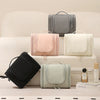 A collection of gray, pink, and cream waterproof hanging toiletry bags displayed on a white surface.