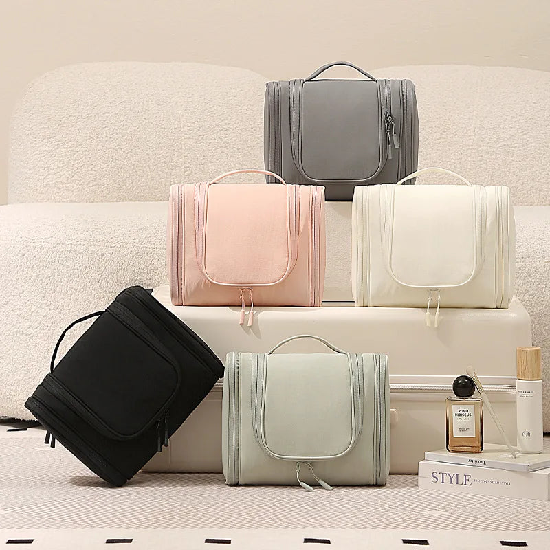 A collection of gray, pink, and cream waterproof hanging toiletry bags displayed on a white surface.