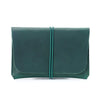 A dark teal minimalist full-grain leather passport holder and card wallet with a stitched closure.