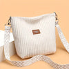 Sac à épaule et bandoulière en velours côtelé de couleur crème pour femme avec une sangle à motifs.