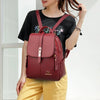 Une femme porte un sac à dos en cuir microfibre marron vintage marron foncé sur un haut noir et un pantalon jaune.