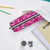 A pink and black zippered pencil case decorated with pink and white animal silhouettes is shown next to a notebook and pencil