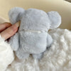 A soft gray plush elephant toy is being held in a white fluffy material.
