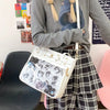 A person is holding a white Y2K punk goth crossbody bag against a background of a gray sweater and plaid skirt.