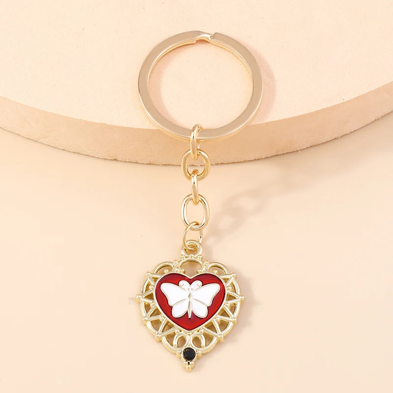 Gold heart-shaped keychain with a white butterfly pendant and a black sun eye detail