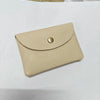 A beige genuine leather card holder with a stitched flap and a round metallic closure.
