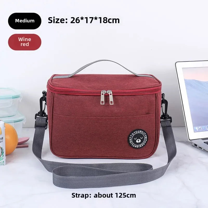 A maroon insulated portable lunch bag with a gray shoulder strap is shown on a white surface.