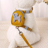 A fluffy white dog wearing a yellow backpack and harness with a leash.