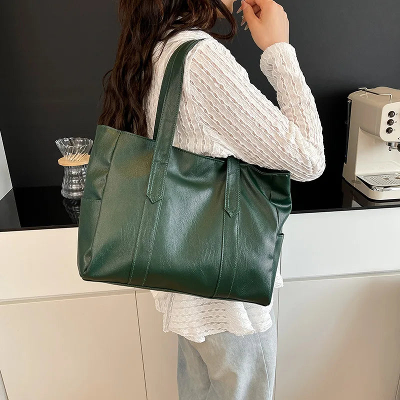 Eine Frau hält eine dunkelgrüne Vintage-PU-Leder-Handtasche vor einem weißen Schrank.