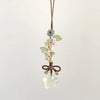 Un délicat pendentif avec un cluster de petites fleurs et feuilles attachées à un charm en forme d'étoile transparente et gla