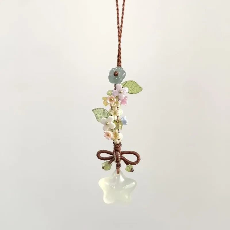 Un délicat pendentif avec un cluster de petites fleurs et feuilles attachées à un charm en forme d'étoile transparente et gla