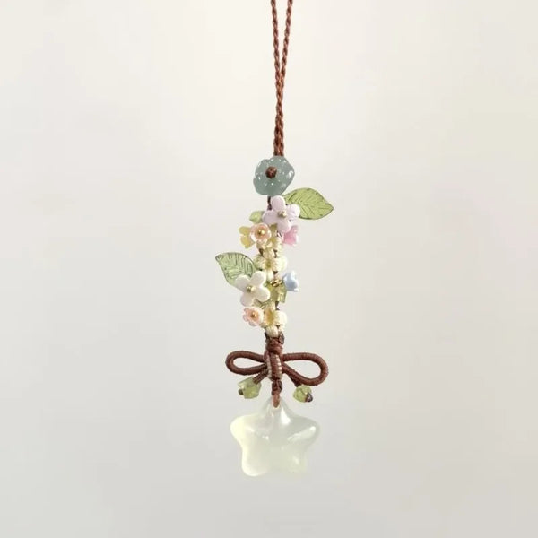 A delicate pendant featuring a cluster of small flowers and leaves attached to a clear, ice-like star-shaped charm on a brown