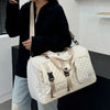 A person holds a cream-colored nylon travel duffle bag with an argyle pattern.