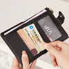 A hand holds a black PU leather bifold wallet with a zipper closure, displaying an ID card.