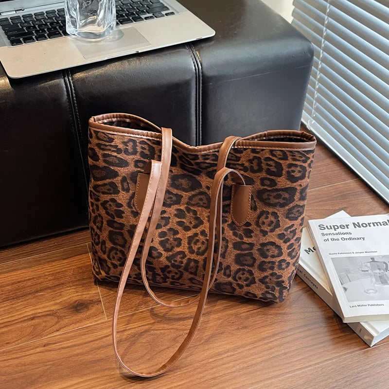 A brown leopard print vintage tote bag resting on a wooden surface next to a laptop and a book.