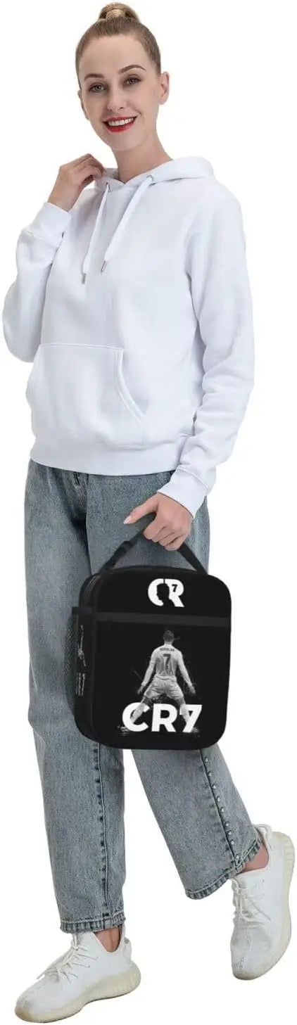 Eine Frau hält eine schwarze wiederverwendbare Oxford-Lunchtasche mit einem weißen Hoodie.