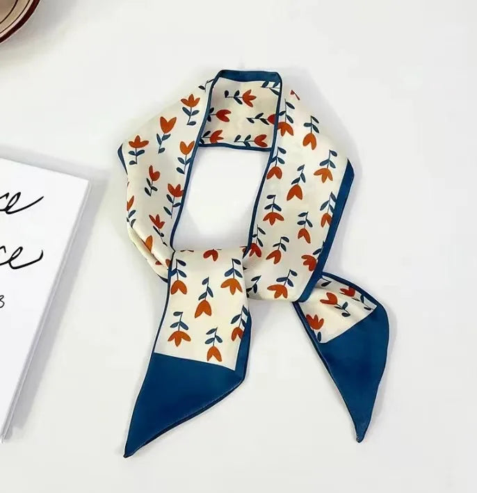 Foulard floral en soie avec fond crème et motifs floraux orange et bleu.
