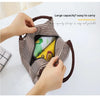 A hand is holding a brown striped Oxford cloth thermal lunch bag open to show its interior storage.