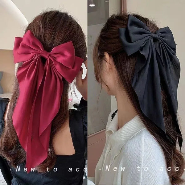 Eine Frau präsentiert eine tiefrote Seidenschleife als Haarschmuck.