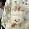 A white bread shaped plush keychain with brown ears attached to a light beige fabric bag.