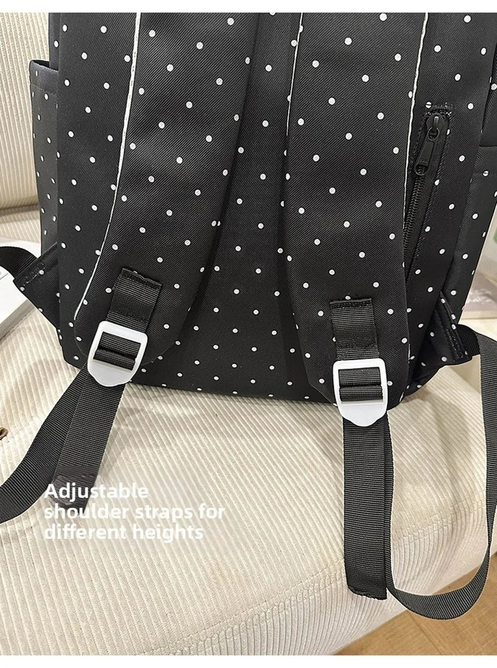 Sac à dos à pois noirs avec sangles d'épaule réglables, montré sur fond clair.