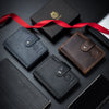 A collection of genuine leather men's business wallets and a red ribbon on a dark surface.