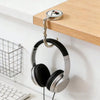 Silver headphones hanging from a wooden shelf hook with a circular plate.