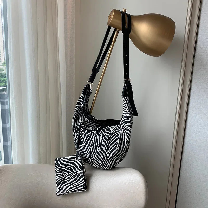 Canvas-Zebra-druck-Crossbody-Tasche mit goldfarbener Lederriemen vor einem Fenster