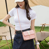 A woman wearing a white t-shirt and denim skirt holds a pink fashion square crossbody bag.
