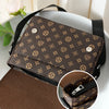 A brown patterned men's casual crossbody bag with a flap design resting on a white surface.