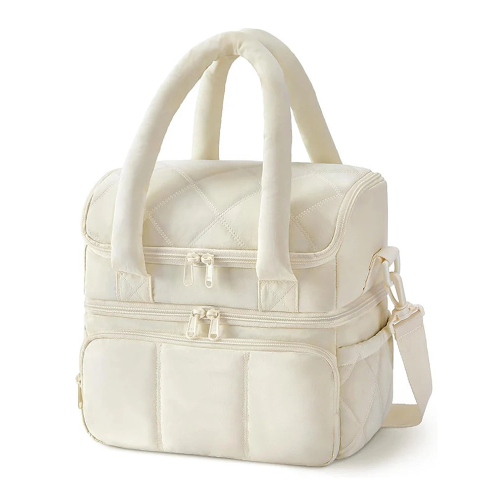 A cream-colored insulated quilted lunch bag with carrying handles and zipper details.