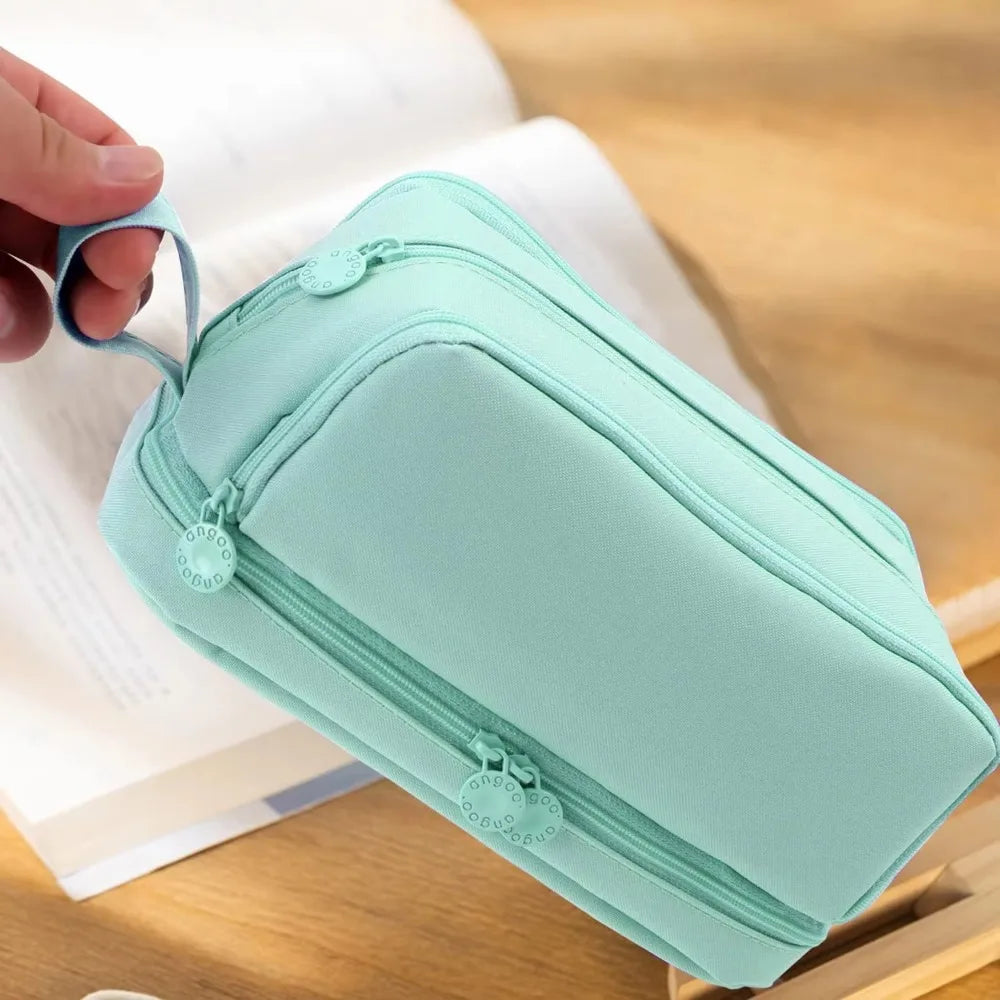 Une trousse à crayons multi-compartiments vert menthe clair ouverte sur une surface en bois.